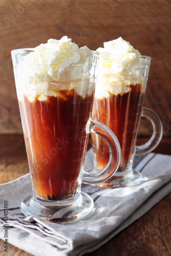 Irish Black coffee with whipped cream in a tall glass on a wooden dark background