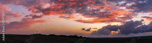 Sun sitting on the horizon against the background of colorful clouds in the sky 