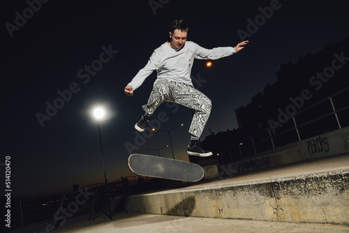 Portrait of cool dude doing stunts on skateboard at night at skateboard there are no people. photo