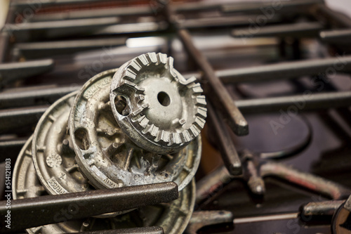 the burners removed from the gas stove lying on the table in the repair shop