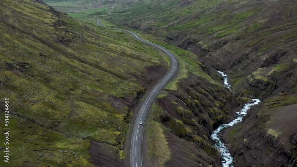 Car driving on winding road in the mountains of Iceland with drone video following. Car driving on winding road in the mountains of Iceland with drone video following.