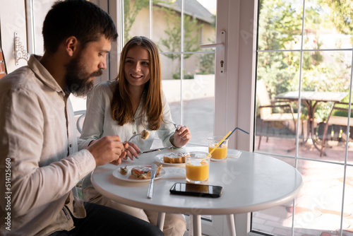 Beautiful couple having breakfast in a stylish cozy cafe, healthy family breakfast