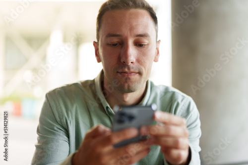 Confident businessman using smartphone sitting in restaurant