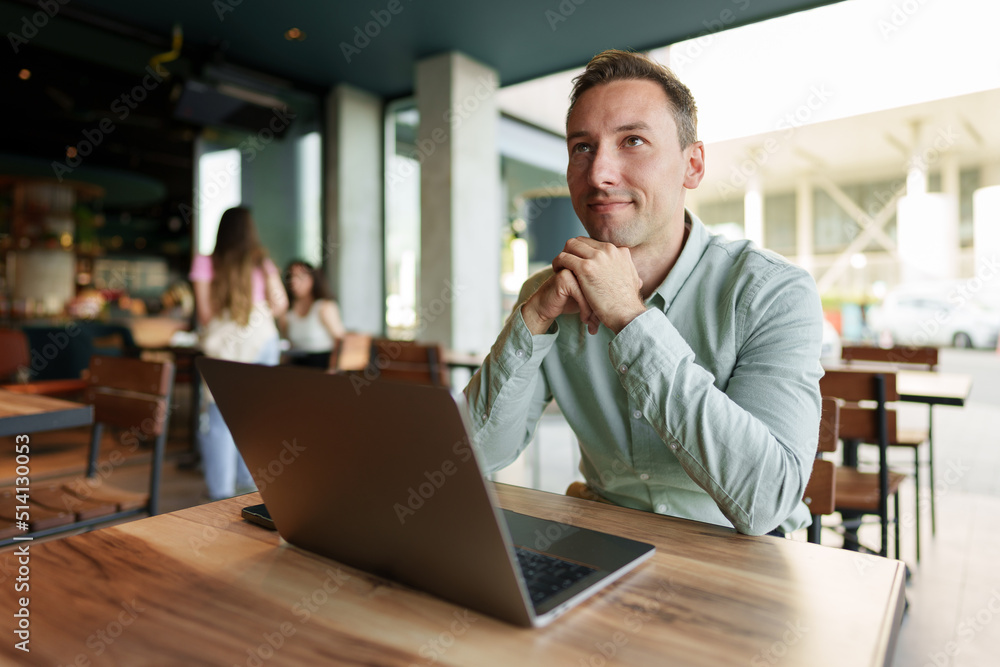 Young businessman sitting in cafe working with laptop computer