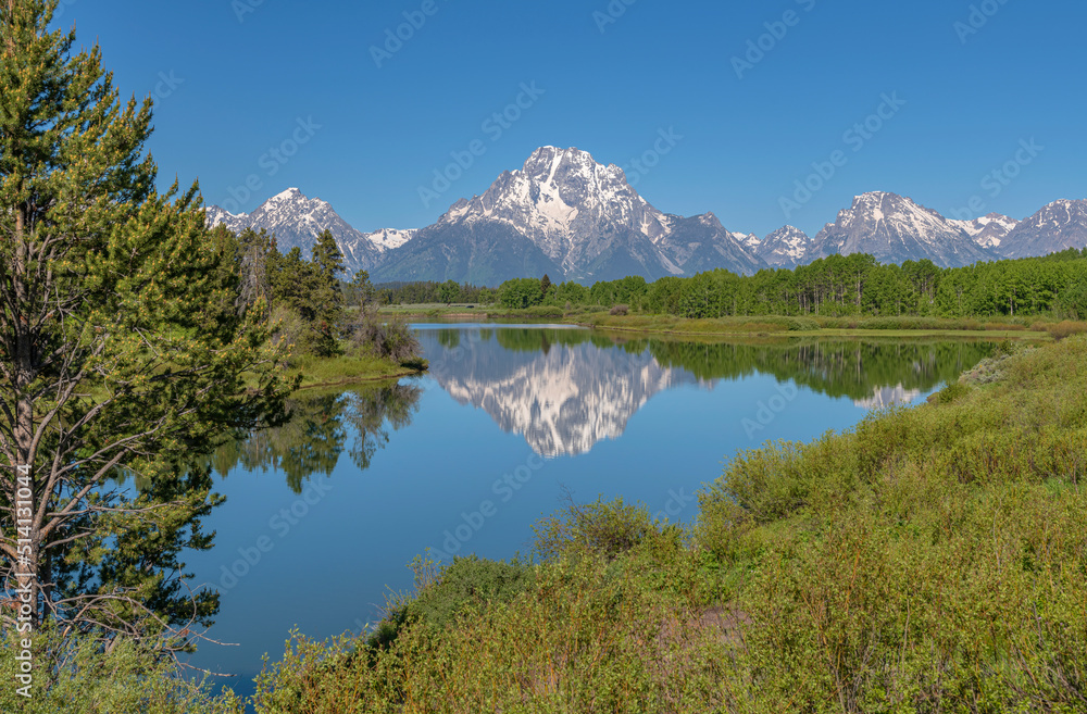 Tetons reflecting on a lake and wilderness.