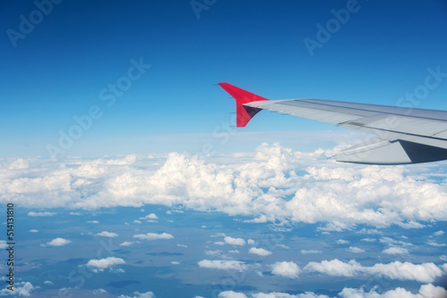 Airplane wing overlooking beautiful clouds in the sky above the earth.