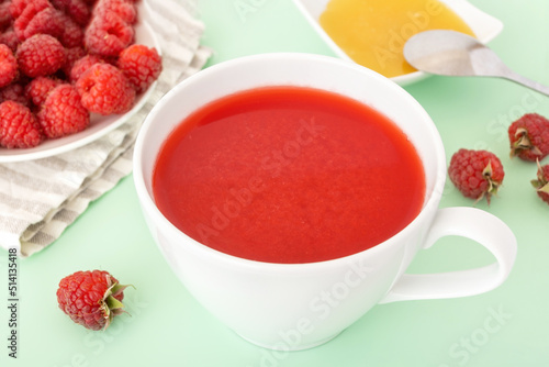 Red raspberry fruit-drink in white cup with paper straw. Healthy summer drink for detox. Colorful antioxidant beverage.