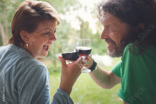 middle-aged couple drinking red wine from glasses outside , hipster man with long hair and beard