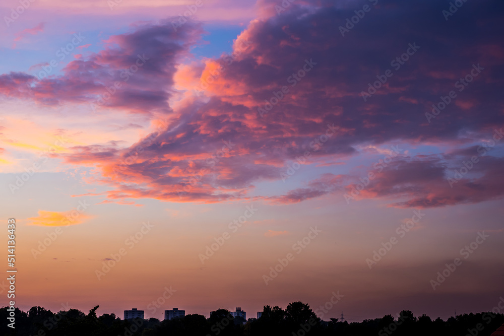 Ominous sunlit colored clouds over landscape at sunset