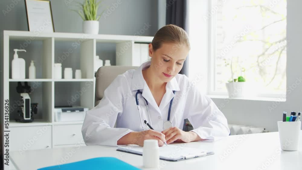 Doctor Works in the Medical Office. Woman in White Coat. Workplace of a Professional Female Therapist in a Hospital or Clinic. Healthcare and Medicine. Doctor Works in the Medical Office. Woman in White Coat. Workplace of a Professional Female Therapist in a Hospital or Clinic. Healthcare and Medicine.
