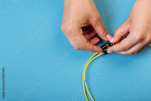 Hands prepare to tune a variable optic attenuator with a screwdriver. Blue background photo