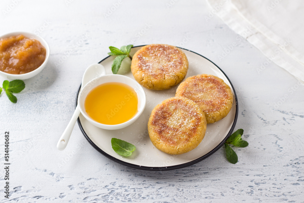Φωτογραφία Tofu and banana cheesecakes, tofniki, with honey and sprinkled with powdered sugar, decorated with mint on a light blue background, top  view