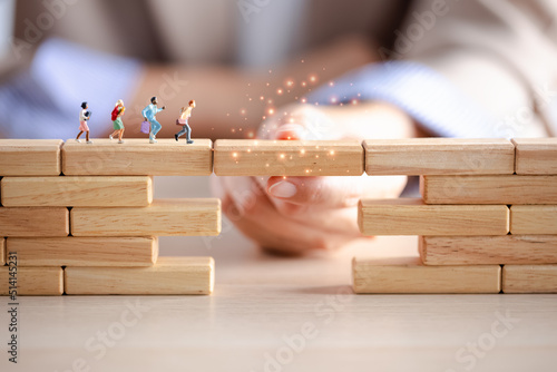 miniature figure running on wood block crossing bridge