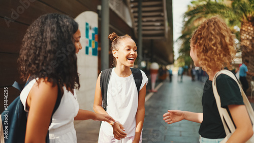 Three girls friends pre-teenage stand on the street smiling and emotionally talking, playing, clapping their hands. Three teenagers on the outdoors in urban cityscape background