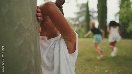 Three girls friends pre-teenage playing Hide-and-seek. Teenage girl counting with closed eyes while others run away