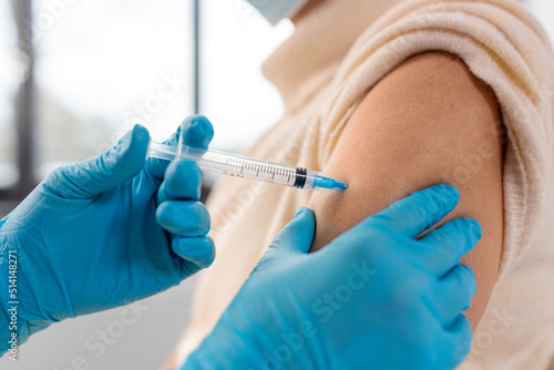 medicine  health and vaccination concept - close up of doctor or nurse with syringe making vaccine or drug injection to woman at hospital