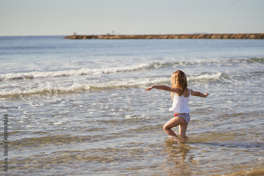 a little girl is playing with the water on the beach a little girl is playing with the water on the beach