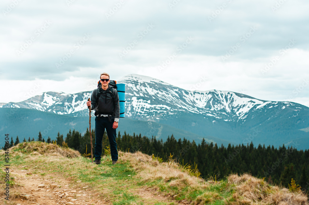 A cute young boy, man with a large tourist, hiking, trekking backpack, stands against the backdrop background of snow-capped mountains, tourism, vacation, vacation, relaxation, weekend, backpacker 