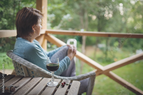 sad middle-aged European woman drinking wine from glass outside summer, alone and looking away