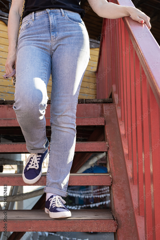 female legs in jeans and sneakers go down the stairs