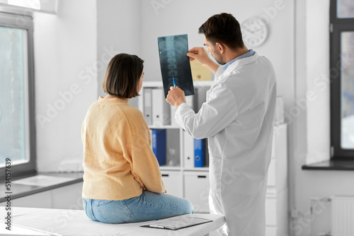 Photos medicine, healthcare and people concept - male doctor showing x-ray to female pa
