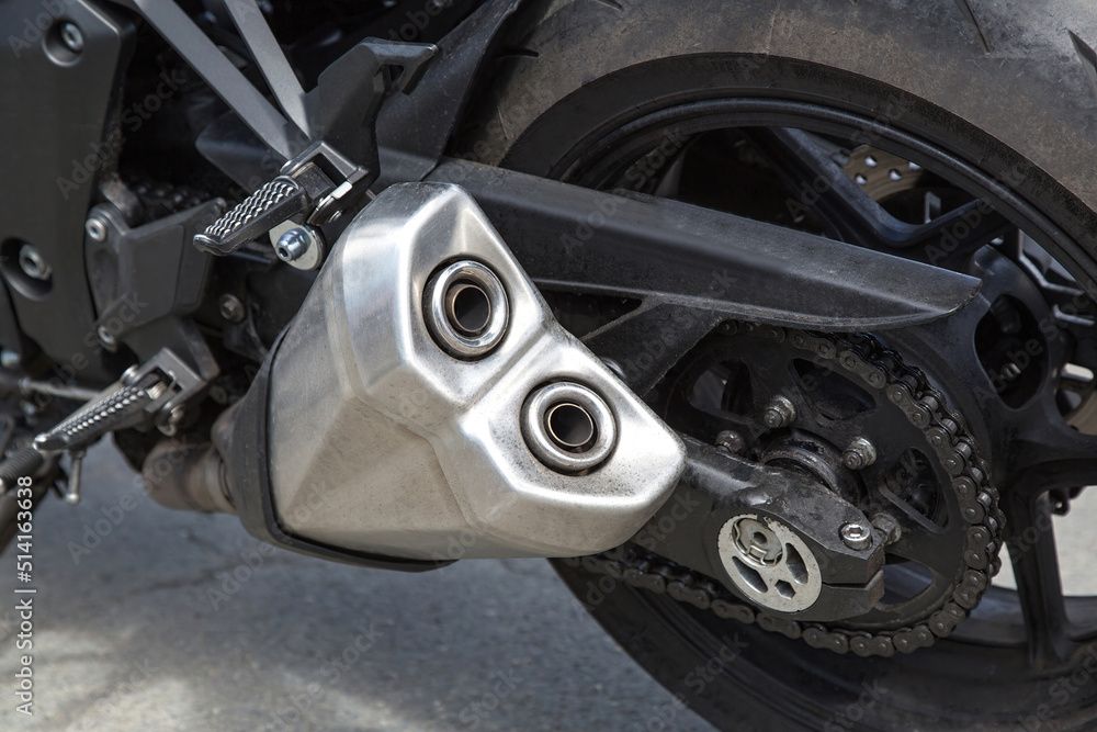 View of the rear wheel of a motorcycle with a chain drive and a twin-pipe muffler