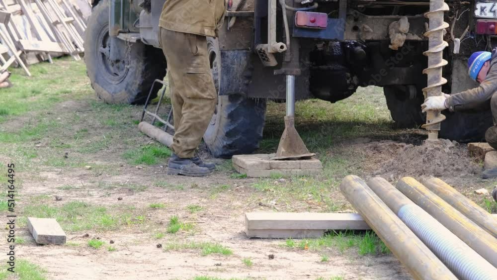 Team of workers with drilling rig on car are drilling artesian well for