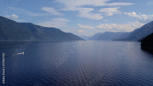 Boats on lake Teletskoye between mountains with blue clear sky in Altai