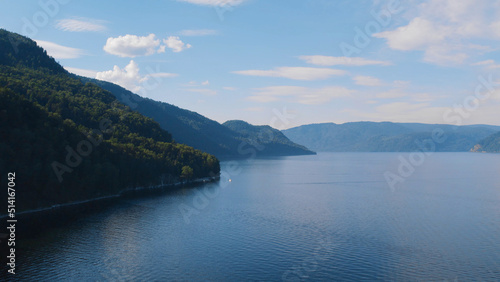 Boats on lake Teletskoye between mountains with blue clear sky in Altai