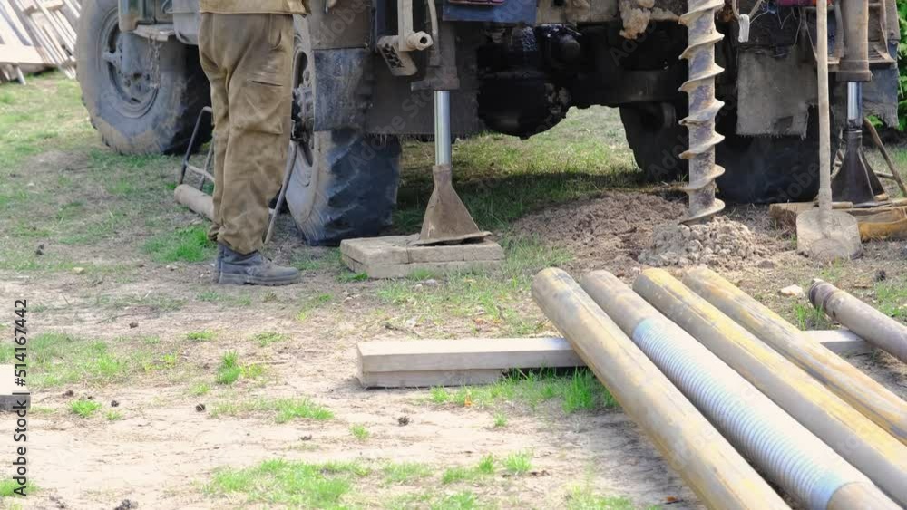 Team of workers with drilling rig on car are drilling artesian well for