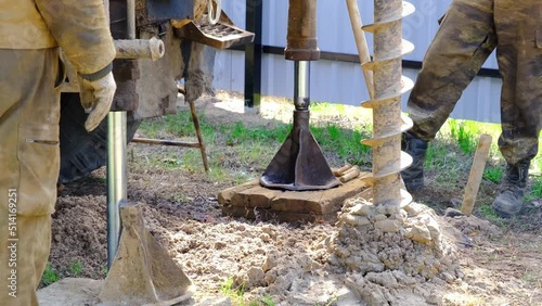 Team of workers with drilling rig on car are drilling artesian well for water in ground. Insertion of metal casing pipe into ground, installation of individual drinking supply, June 28, 2022, Russia, 