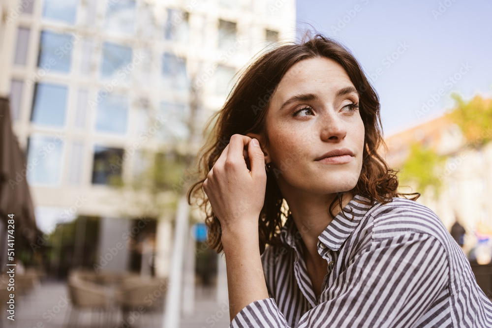 serious young woman sitting in city looking to the side serious young woman sitting in city looking to the side