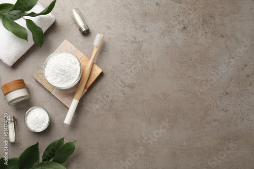 Flat lay composition with tooth powder and green leaves on grey table, space for text