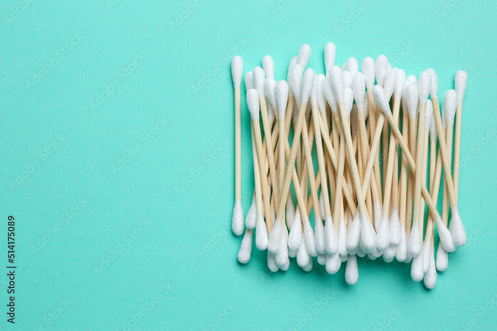 Heap of cotton buds on turquoise background, top view. Space for text Heap of cotton buds on turquoise background, top view. Space for text