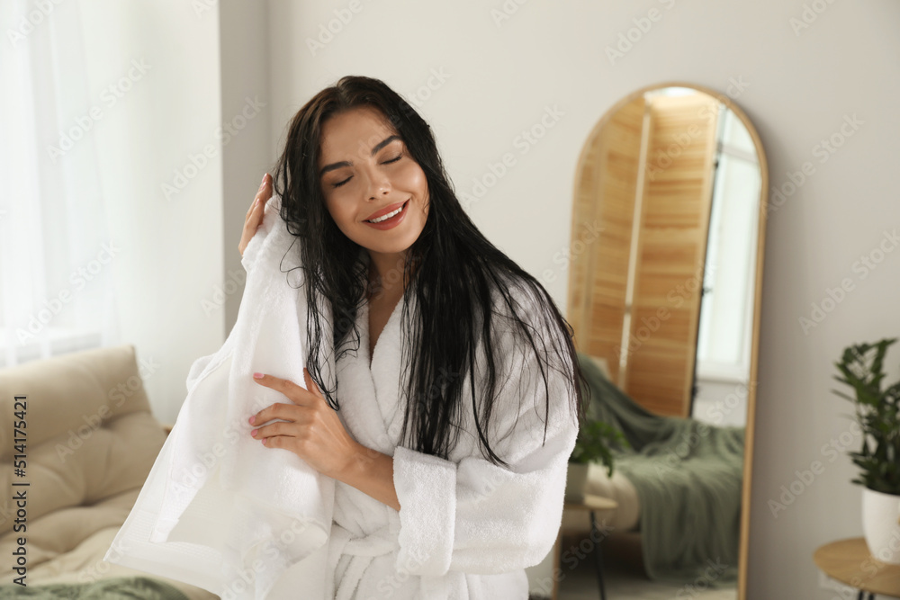 Beautiful young woman in bathrobe drying hair with towel indoors - obrazy, fototapety, plakaty 
