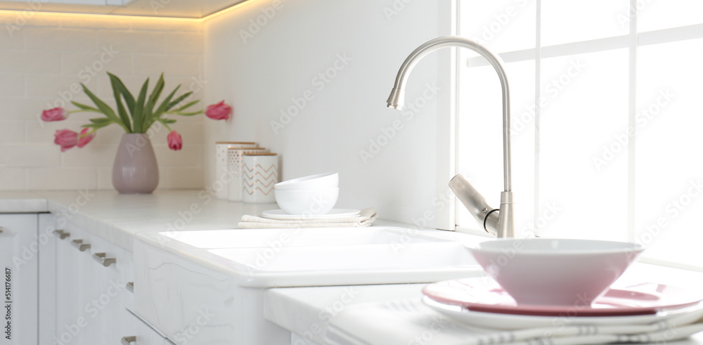 Fototapeta premium Beautiful ceramic dishware and bouquet on countertop in kitchen. Banner design