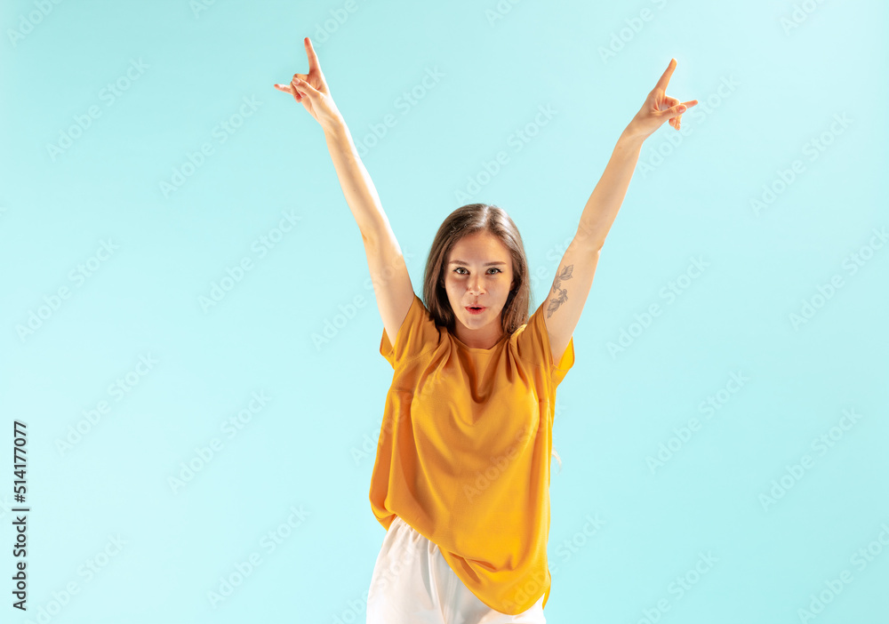Portrait of beautiful young girl showing excitement, posing isolated over blue studio background. Winner Portrait of beautiful young girl showing excitement, posing isolated over blue studio background. Winner