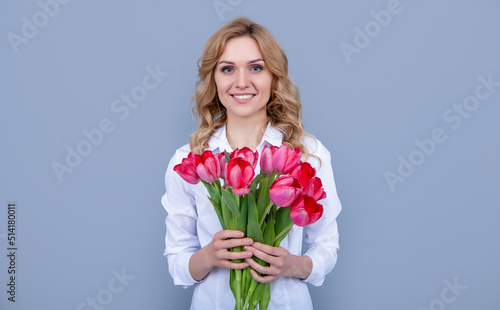positive girl with spring tulip flowers on grey background