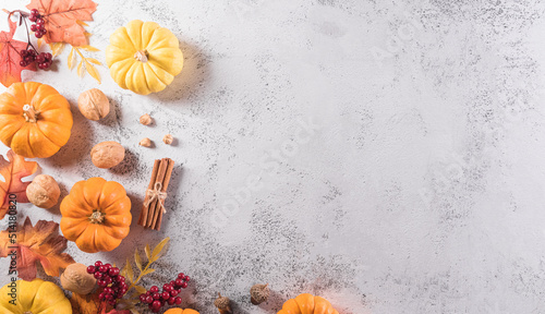Autumn and thanksgiving decoration background concept with fall leaves, pumpkin and seasonal autumnal decor on stone background, top view, copy space.