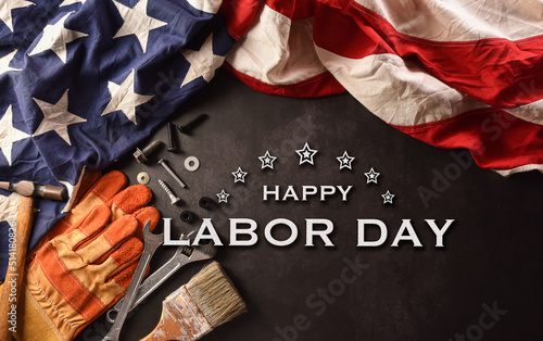 Happy Labor day concept. American flag with different construction tools and the text on dark stone background. photo