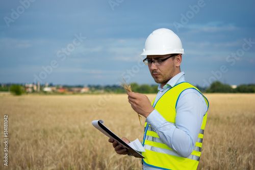 Agro engineer at the field inspection, the farmer stands in a wheat field with a folder in his hands and checks the harvest, the engineer stands in a field with wheat