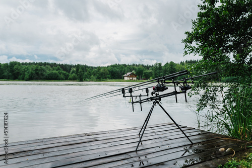 Spinning. Fishing with signaling devices on holder. Feeder fishing with reel. Rod pod. Fishing rods for pike, perch, carp on pond. Angler with fishing technique. World Fisherman's Day, photo article.