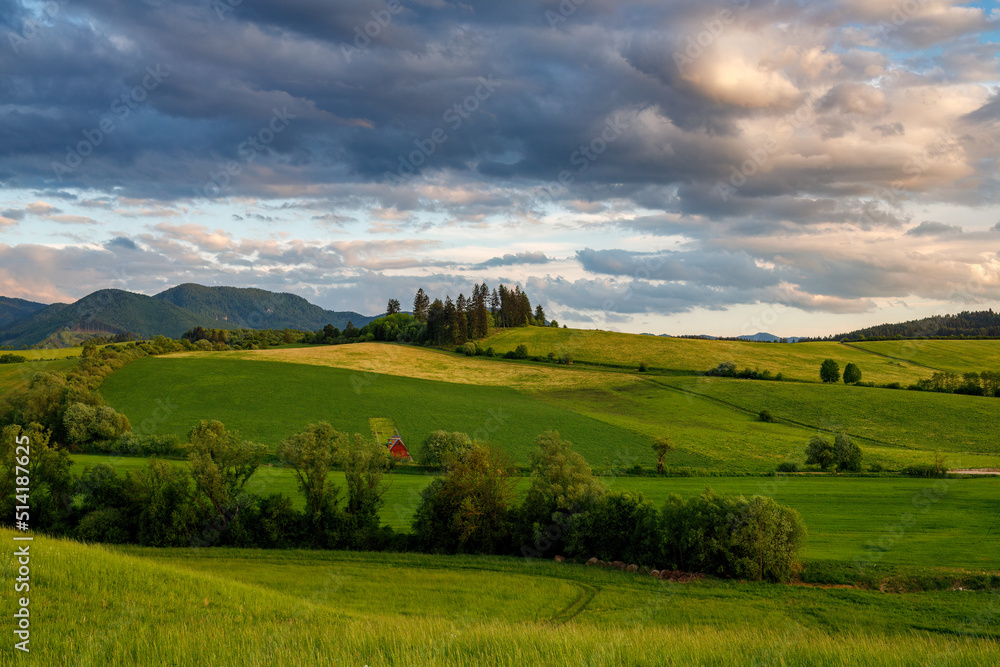 Spring rural landscape with dramatic sky at sunset. Meadows on the hillside of the Little Fatra Mountains in Slovakia, Europe.