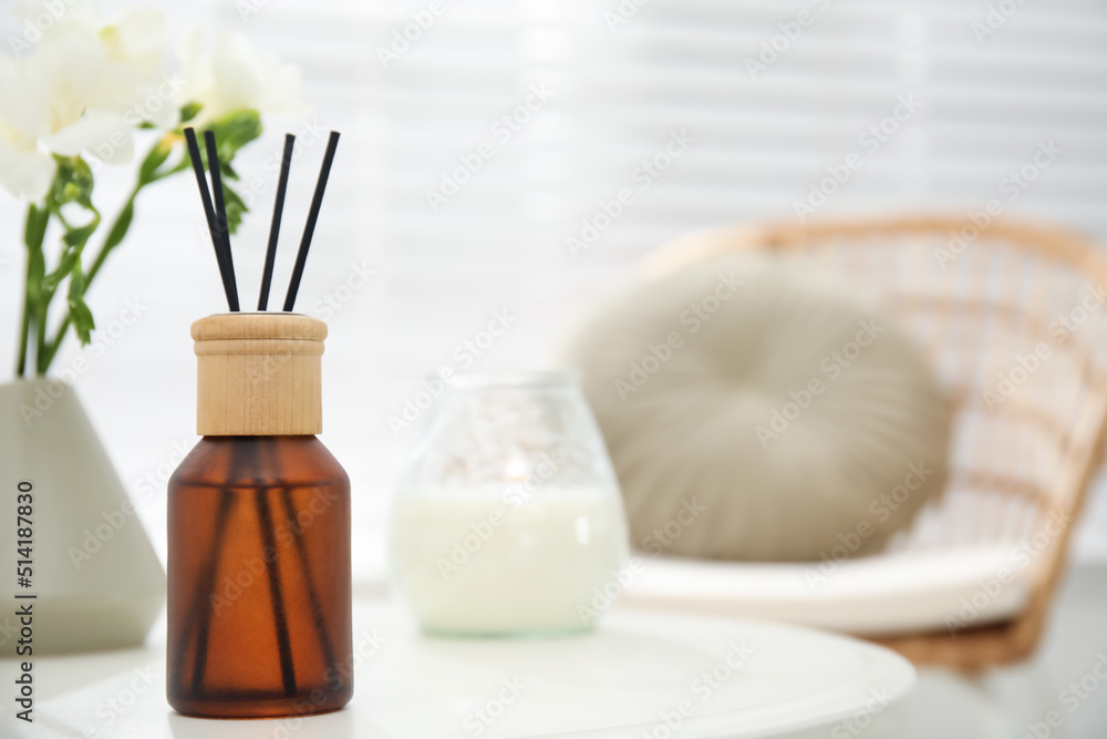 Reed diffuser and home decor on white table in room. Space for text