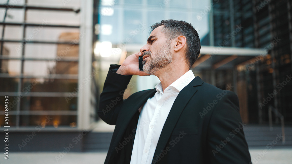 Middle-aged businessman with neat beard in office clothes uses mobile phone. Successful man emotionally talking on smartphone. Disappointment, trouble Middle-aged businessman with neat beard in office clothes uses mobile phone. Successful man emotionally talking on smartphone. Disappointment, trouble