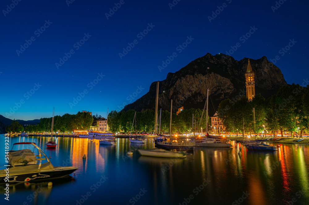 The city of Lecco, with its lakefront and its buildings, photographed in the evening.