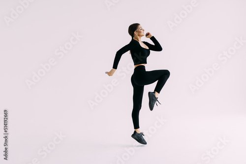 Portrait of a smiling fitness woman jumping isolated over white background