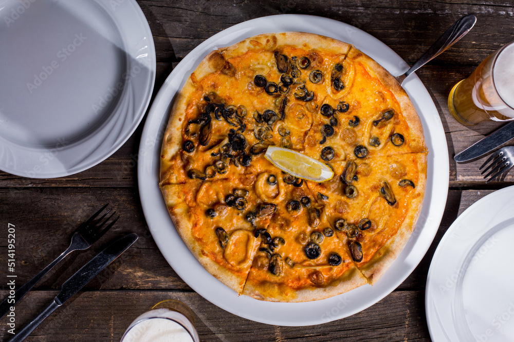 Pizza with mussels, squid rings, olives, lemon and cheese