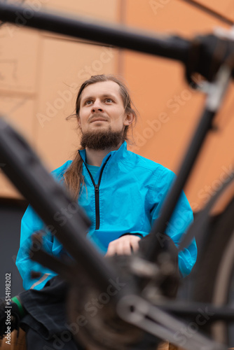 Portrait of a male cyclist with a beard and long hair through the bike