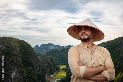 Turista con sombrero vietnamita disfrutando de las vistas de Ninh Binh, en Vietnam